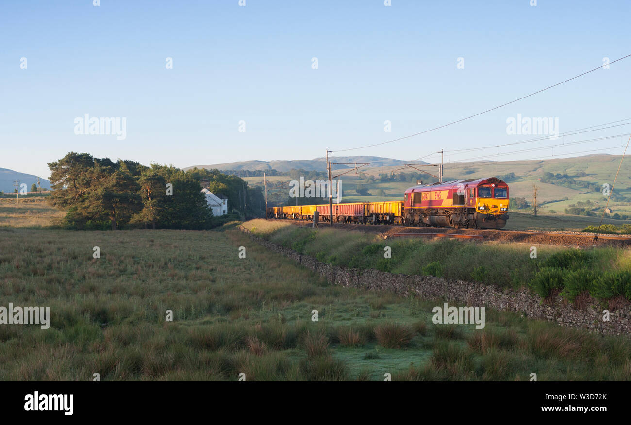 DB Cargo UK Class 66 Lokomotive vorbei Scout Grün auf dem West Coast Mainline in Cumbria mit einem Güterzug mit Materialien für Network Rail Stockfoto