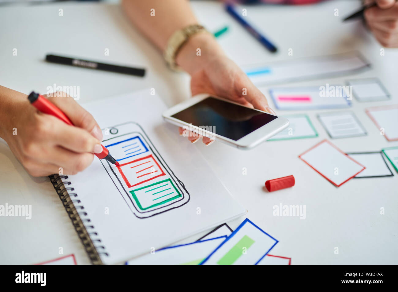 Nahaufnahme von Frau Zeichnung website Wireframes auf Papier beim Brainstorming mit Kollegen Stockfoto