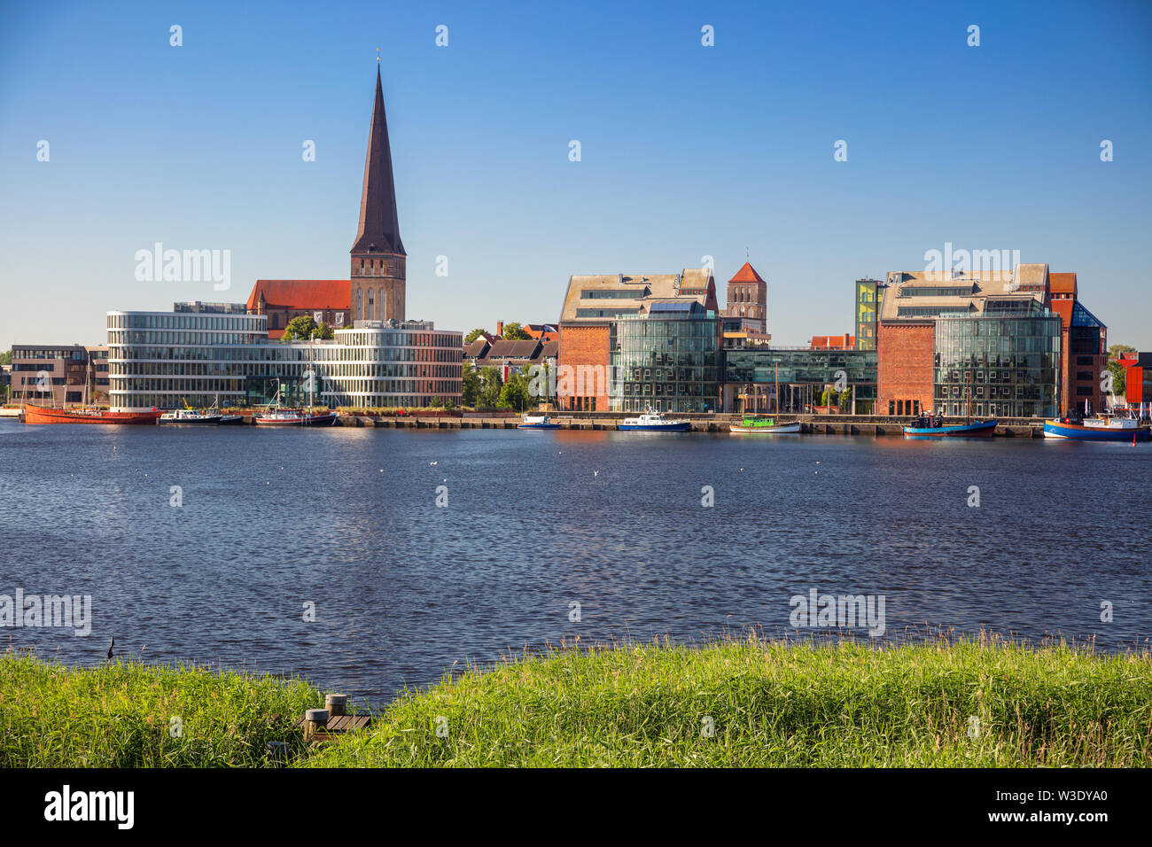 Rostock, Deutschland. Stadtbild Rostocker Flussufer mit Peterskirche im sonnigen Sommertag. Stockfoto