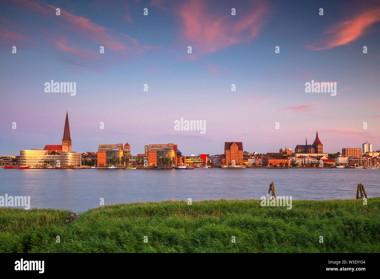 Rostock, Deutschland. Stadtbild des Rostocker Flussufers mit der Peterskirche bei Sommeruntergang. Stockfoto