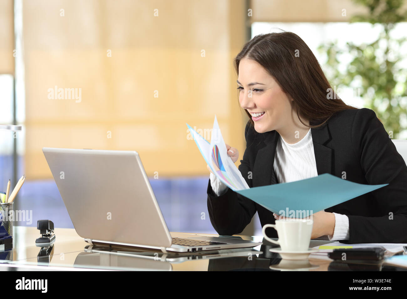 Happy executive Vergleich Laptop online Inhalte und Dokumente auf Papier im Büro Stockfoto