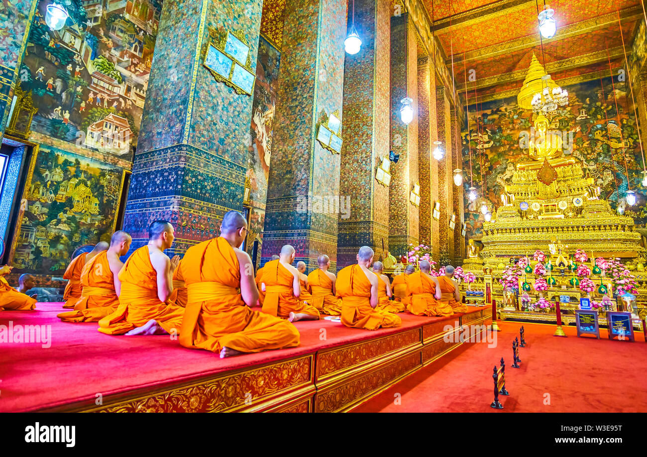 BANGKOK, THAILAND - 22 April, 2019: Die Mönche sitzen auf den Knien vor dem ubosot mit goldenen Statue des Buddha auf der Oberseite im Wat Pho Tempel Kom Stockfoto