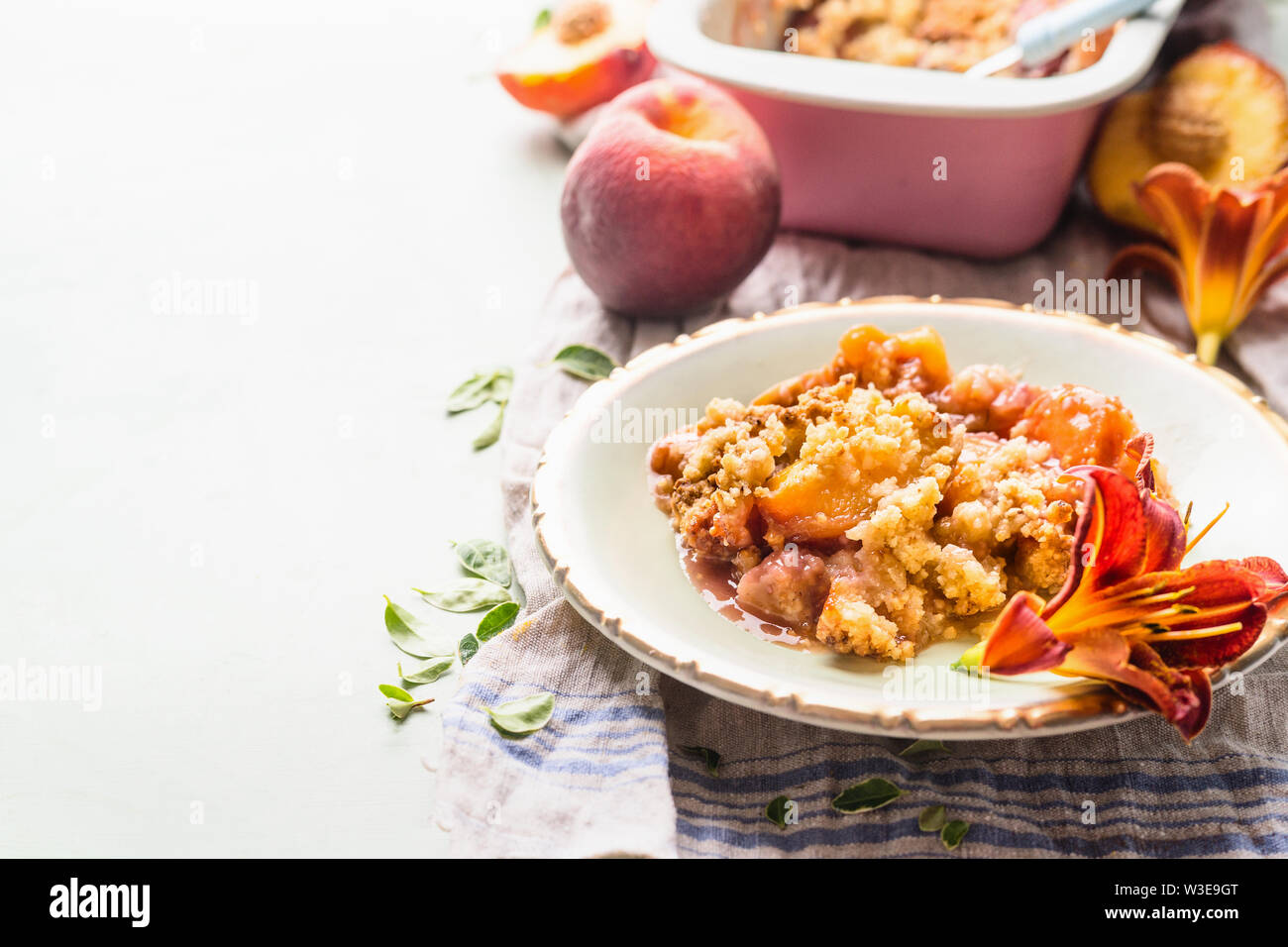 Nahaufnahme von köstlichen Peach cobbler Dessert in der Platte auf hellen Hintergrund mit Backblech und frische Pfirsiche. Platz kopieren Stockfoto