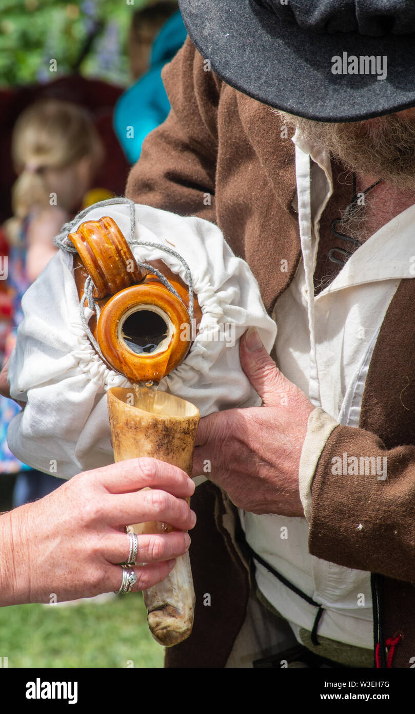 Reenactor in mittelalterlichen Kostüm gießen einen Drink in Horn Schale Stockfoto