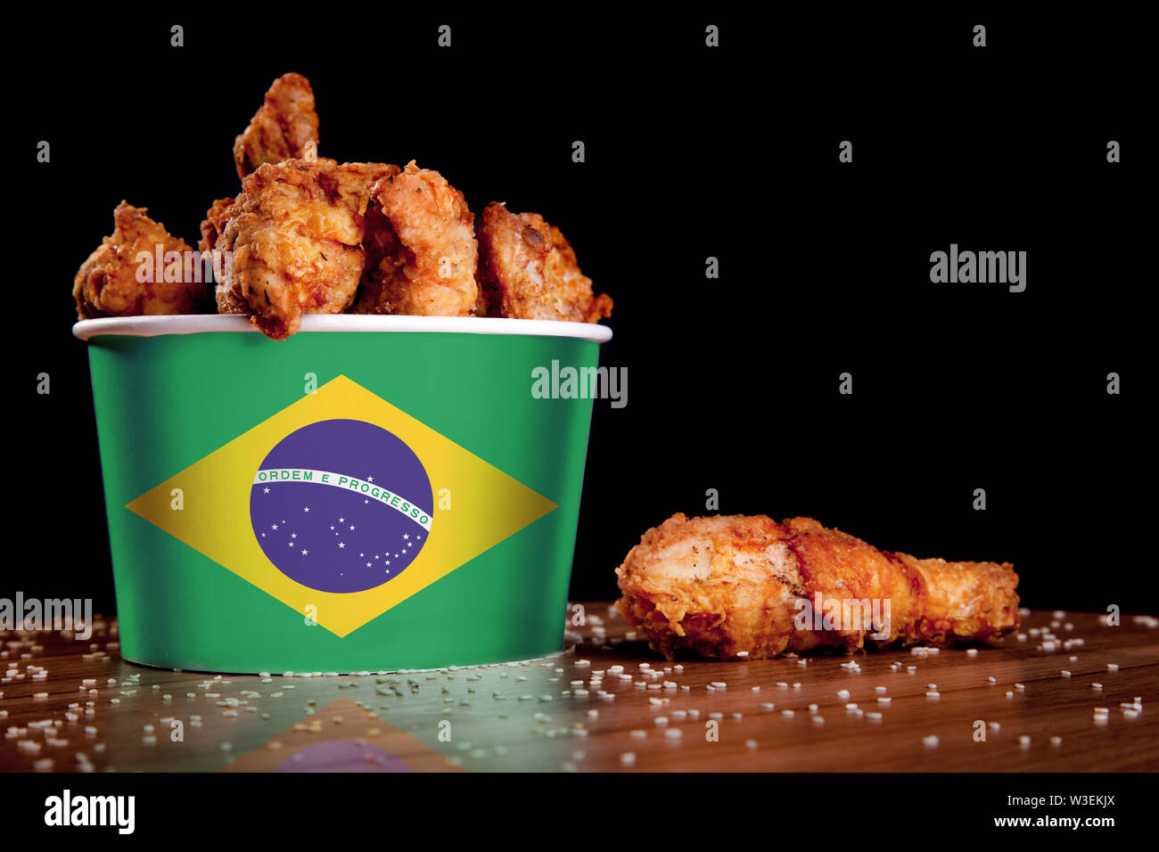 BBQ Hähnchenschenkel im Eimer Flagge von Brasilien auf einem Holztisch und schwarzen Hintergrund. Stockfoto