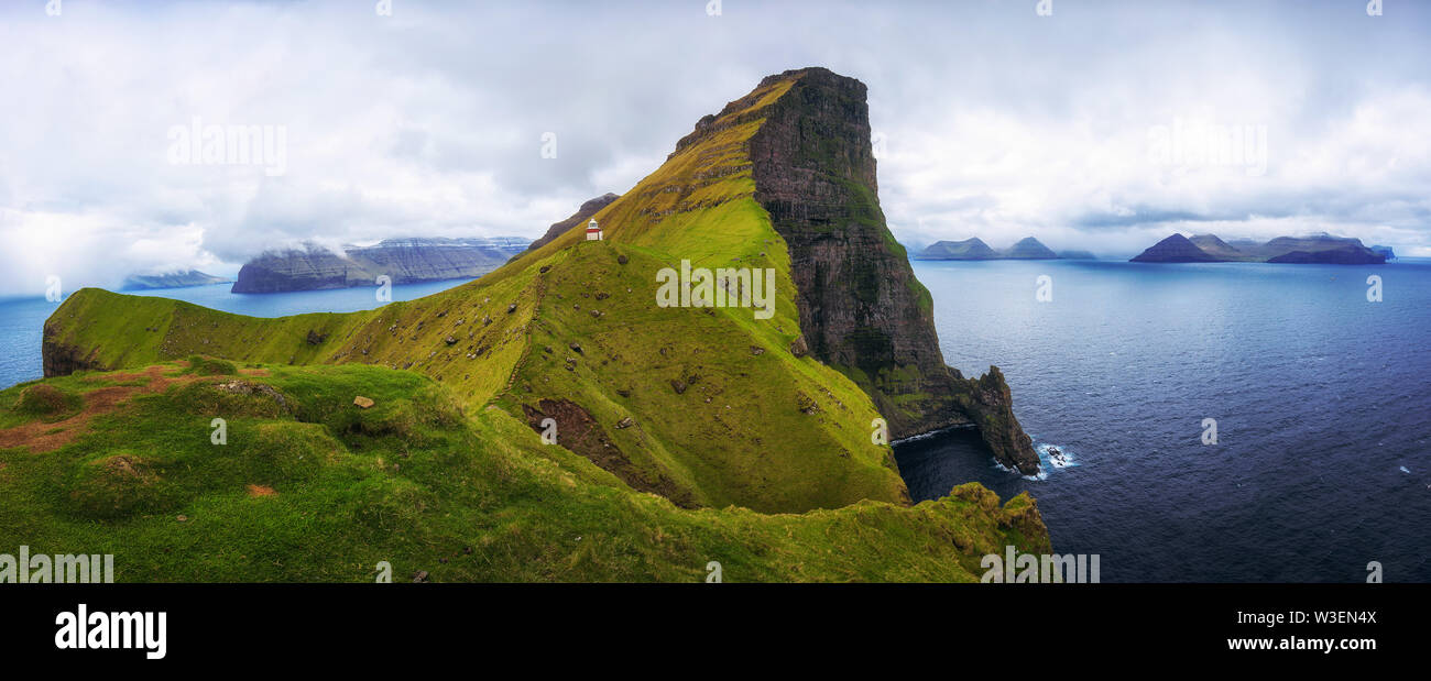 Kleine Leuchtturm in der Nähe von riesigen Felsen auf der Insel Kalsoy, Färöer Inseln Stockfoto