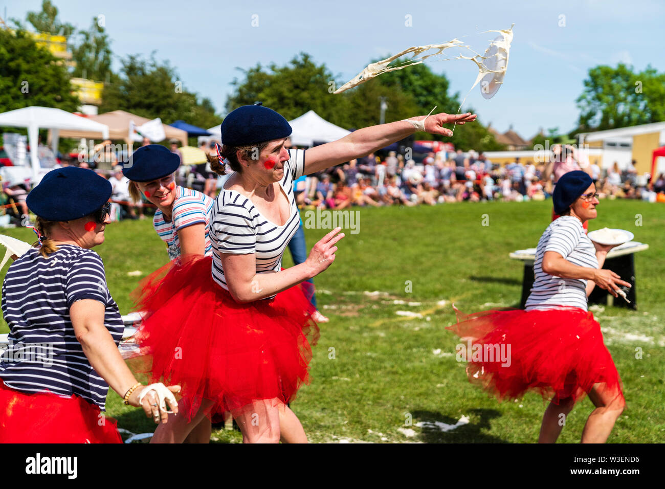 Welt Custard Pie-Meisterschaft. Frauen Mannschaft, "die französische Torten "hurling Custard pies an unseen gegnerische Team. Das Tragen der roten Rüschen Röcke und baskenmützen. Stockfoto