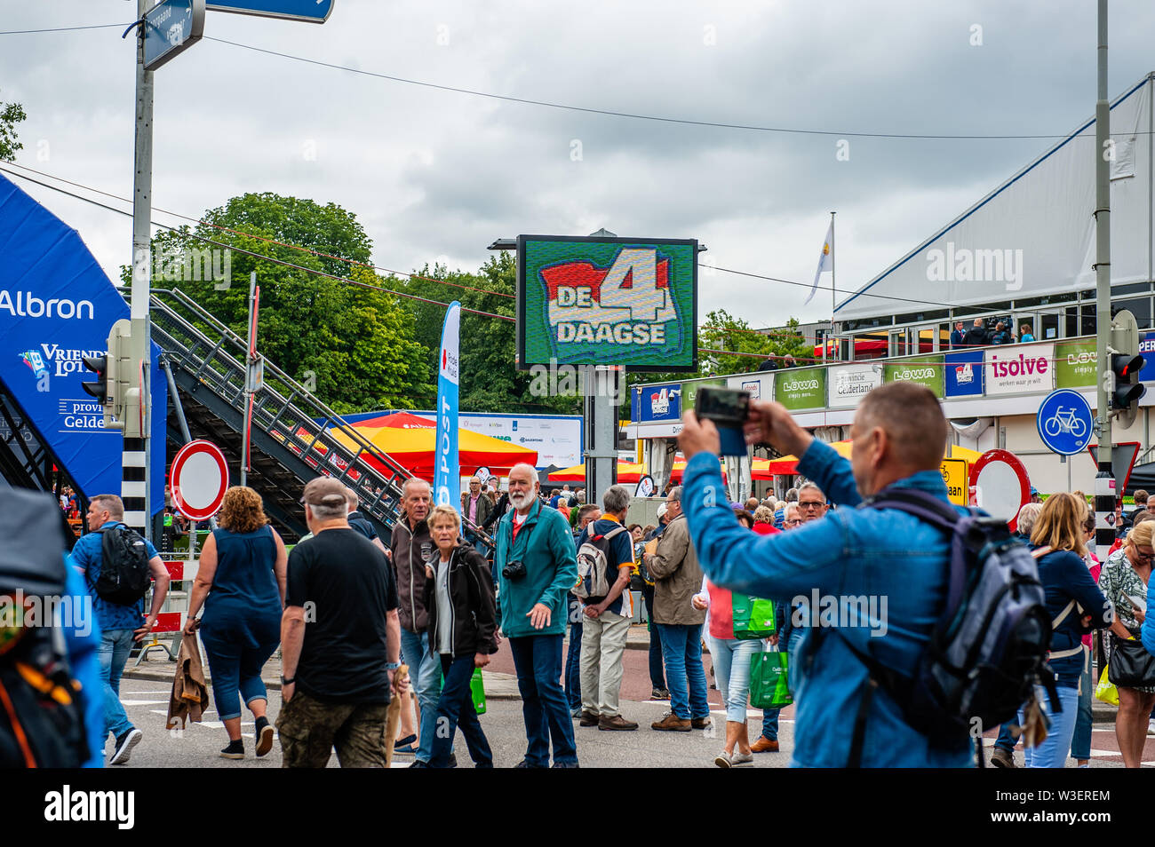 Ein Mann nimmt Fotos am Ausgangspunkt der Walking Event. Die Internationale vier Tage marschiert, genannt "Vierdaagse in Nimwegen in den größten Multi gewachsen ist - Tag Walking Event in der Welt. Der Tag vor, alle Wanderer gehen Ihre Armband mit der Anzahl der Registrierung am Anfang der Spaziergang abzuholen. Stockfoto