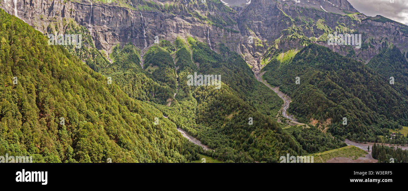 Drone Ansicht eines alpine River Valley und üppig grüne alpine Wälder umgeben von hohen Bergen. Stockfoto