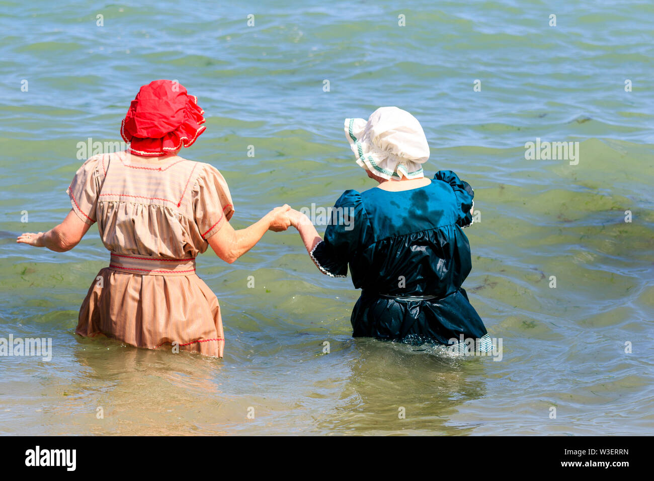 Broadstairs jährliche Dickens Festival. Ansicht der Rückseite zwei ältere Frauen, die zu Fuß zu ihren Taillen im Meer beim Tragen viktorianische Badeanzüge. Stockfoto