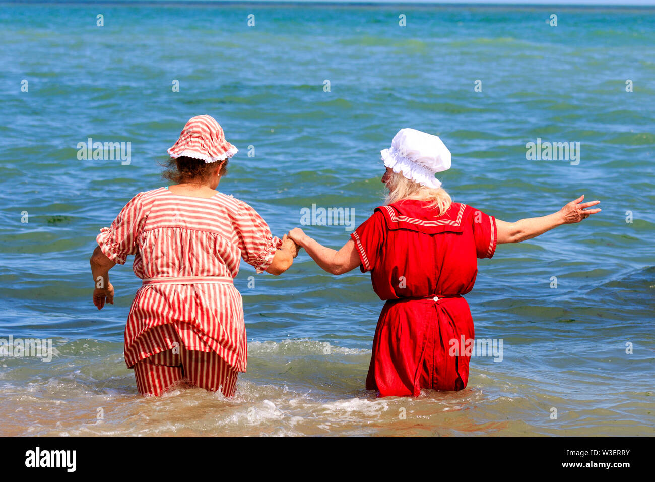 Broadstairs jährliche Dickens Festival. Ansicht der Rückseite zwei ältere Frauen, die zu Fuß zu ihren Taillen im Meer beim Tragen viktorianische Badeanzüge. Stockfoto