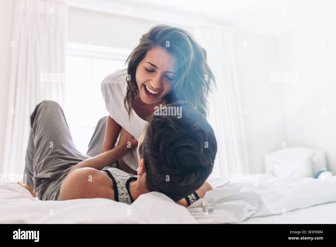 Lächelnde junge Frau in Spielerische mit ihrem Freund im Bett. Paar Spaß im Bett. Stockfoto