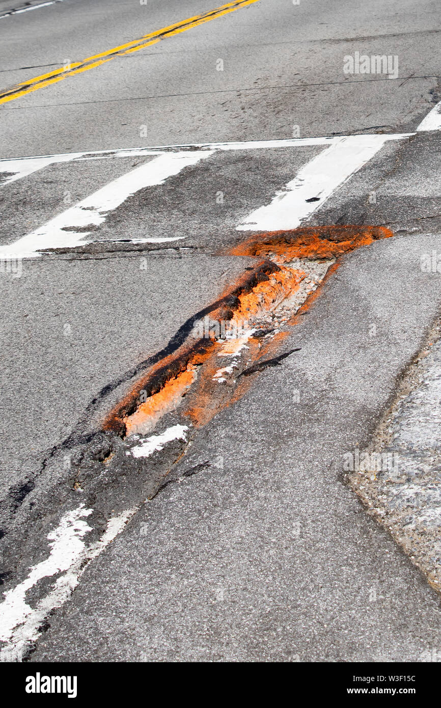 Schlaglöcher im Asphalt auf einer Straße in Spekulant, NY, USA, eine Gefahr für die Autofahrer. Stockfoto
