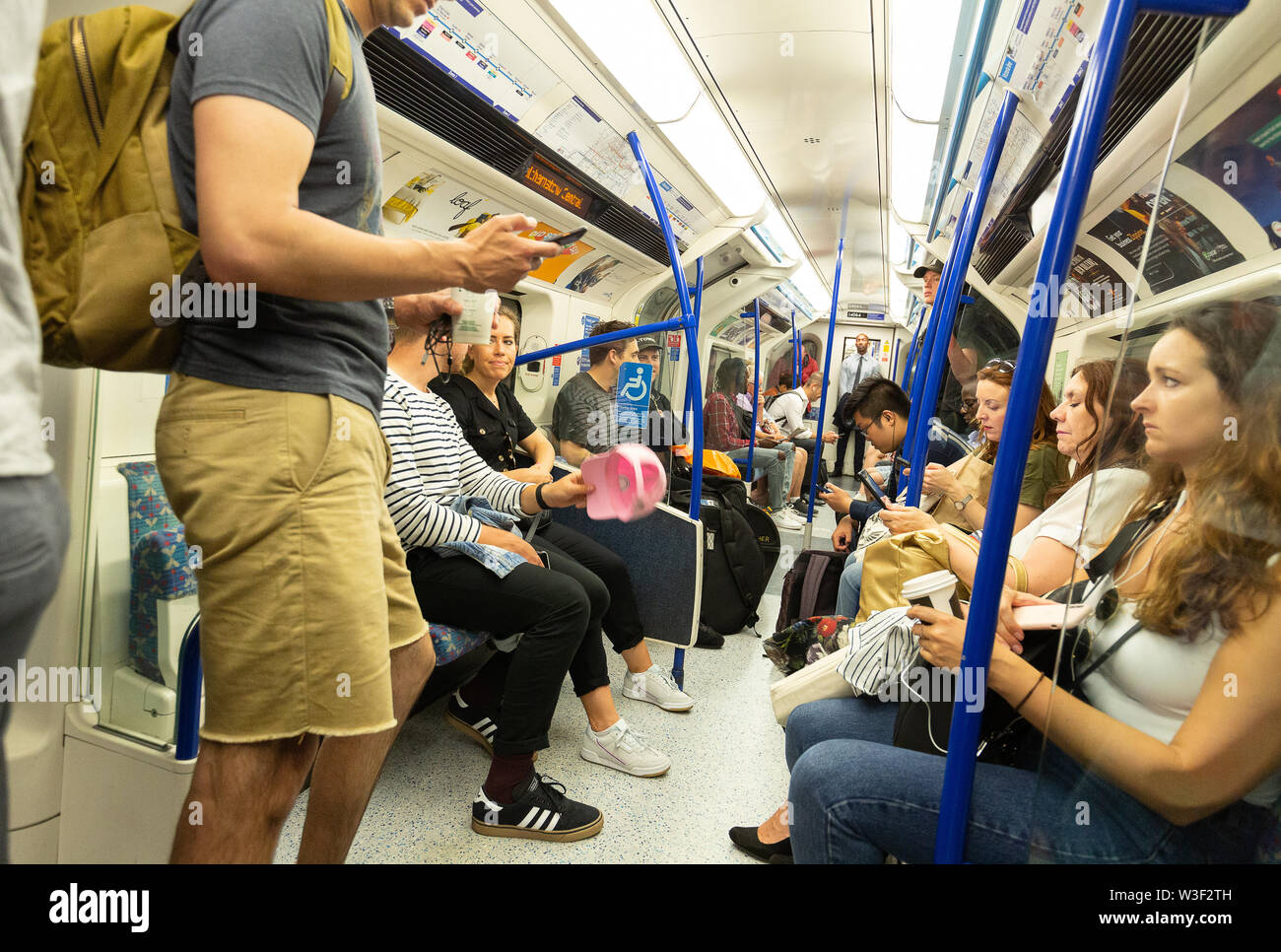 Die Londoner U-Bahn Handy; ein Passagier mit einem Handy in der tube Waggon voller Menschen, London UK Stockfoto