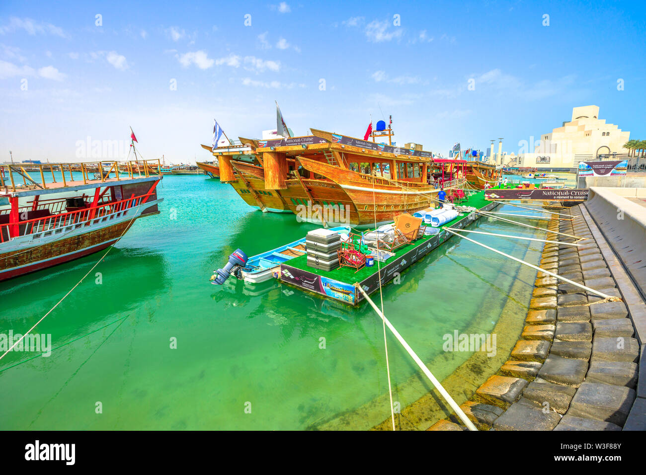 Doha, Katar - Februar 16, 2019: Vielen hölzernen Dhaus, die mit Beginn der Dhow Hafen mit Museum für Islamische Kunst in Doha Bucht auf dem Hintergrund angedockt. Mitte Stockfoto