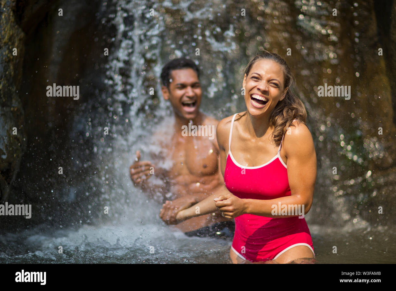Glückliches junges Paar in der Nähe von einem Wasserfall zu lachen. Stockfoto