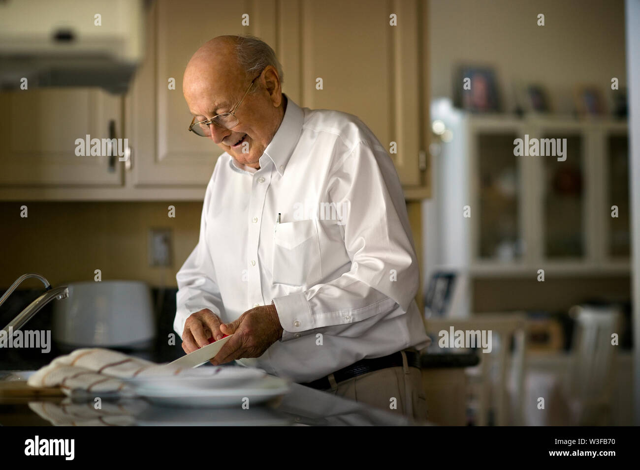 Älterer Mann reinigt bis in die Küche nach dem Mittagessen. Stockfoto