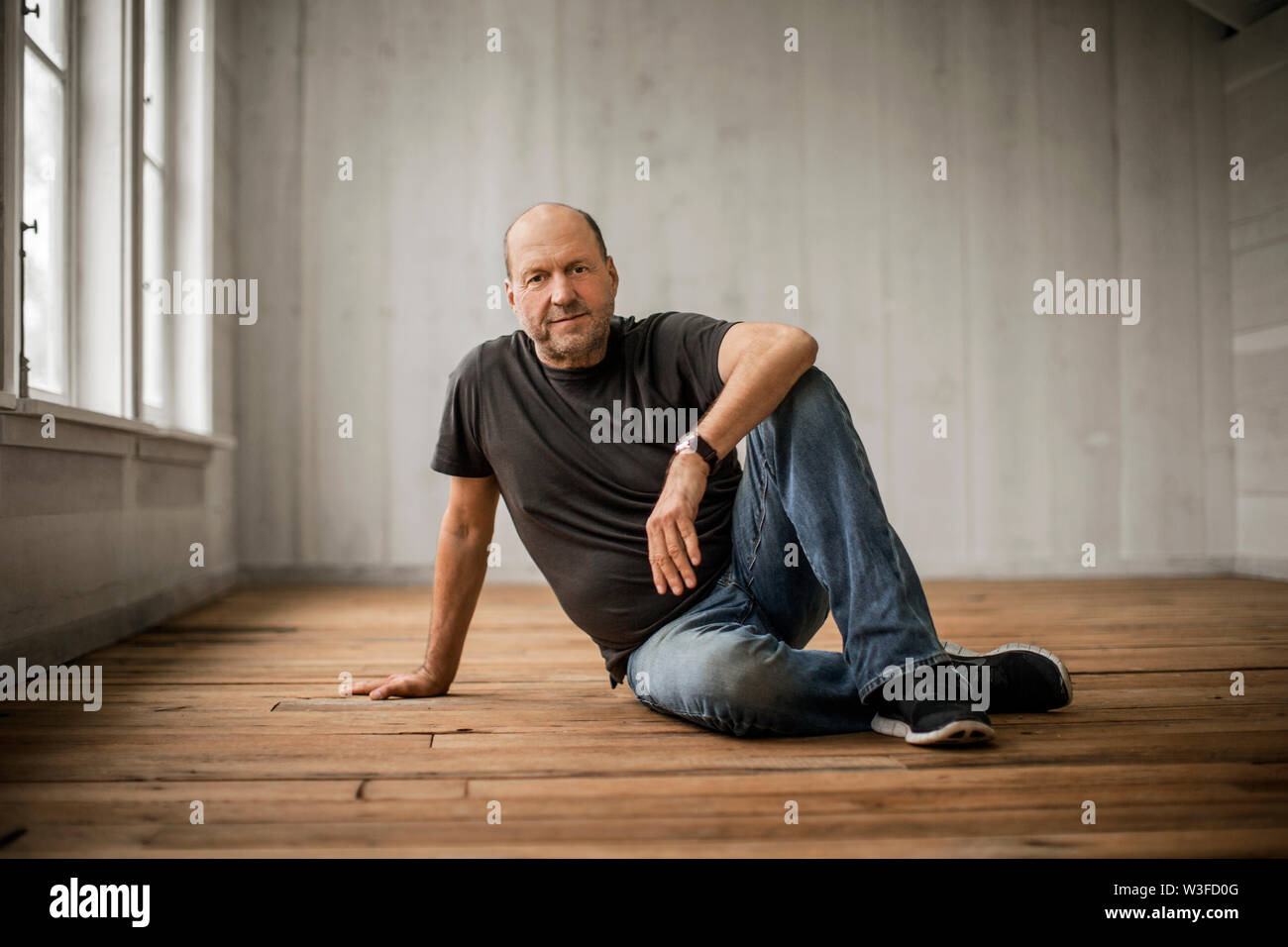 Porträt eines mittleren Alter Mann sitzt auf einem Parkettboden. Stockfoto