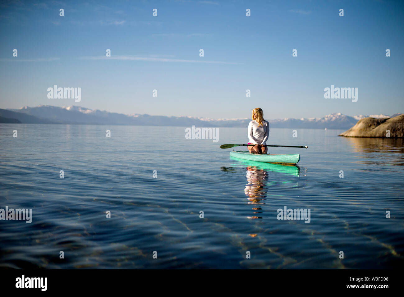 Aktive junge Frau paddleboarding über einen See. Stockfoto