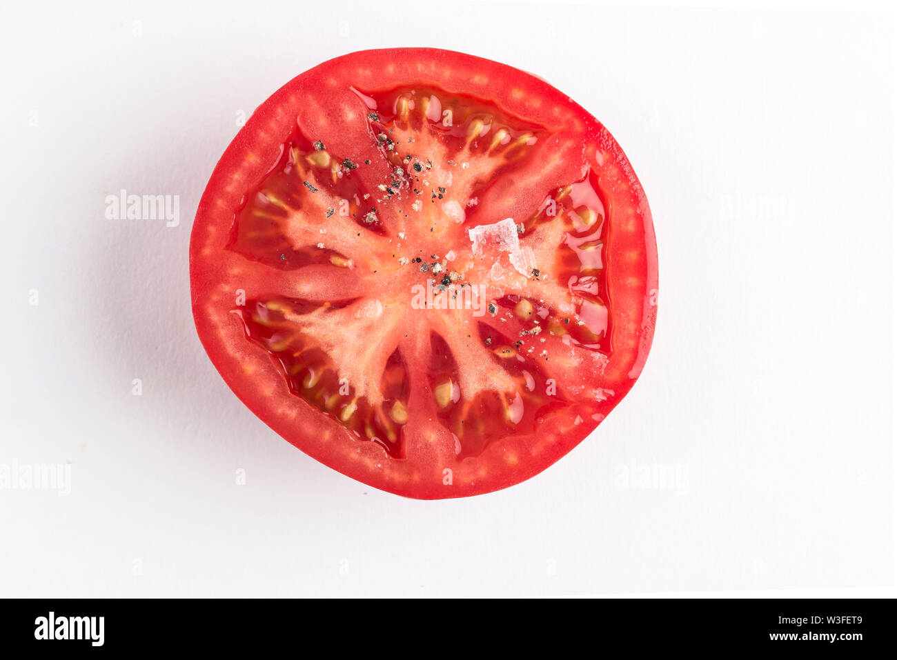 Eine halbe Erbe Tomate mit Salz und schwarzer Pfeffer Stockfoto