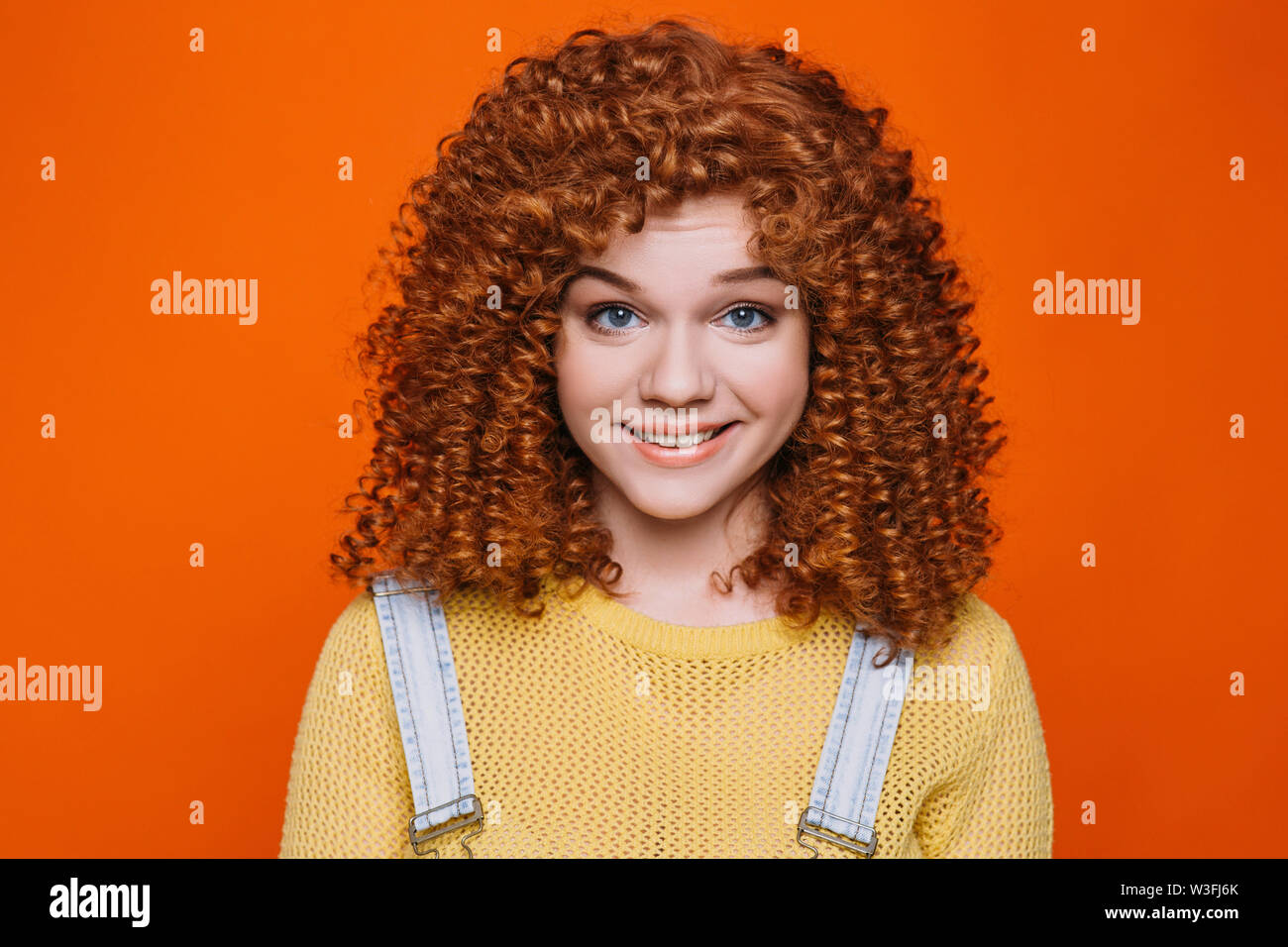 Schöne rothaarige Frau mit perfekten lockiges Haar Lächeln auf die Kamera schaut. Perfekte locken Frisur Stockfoto