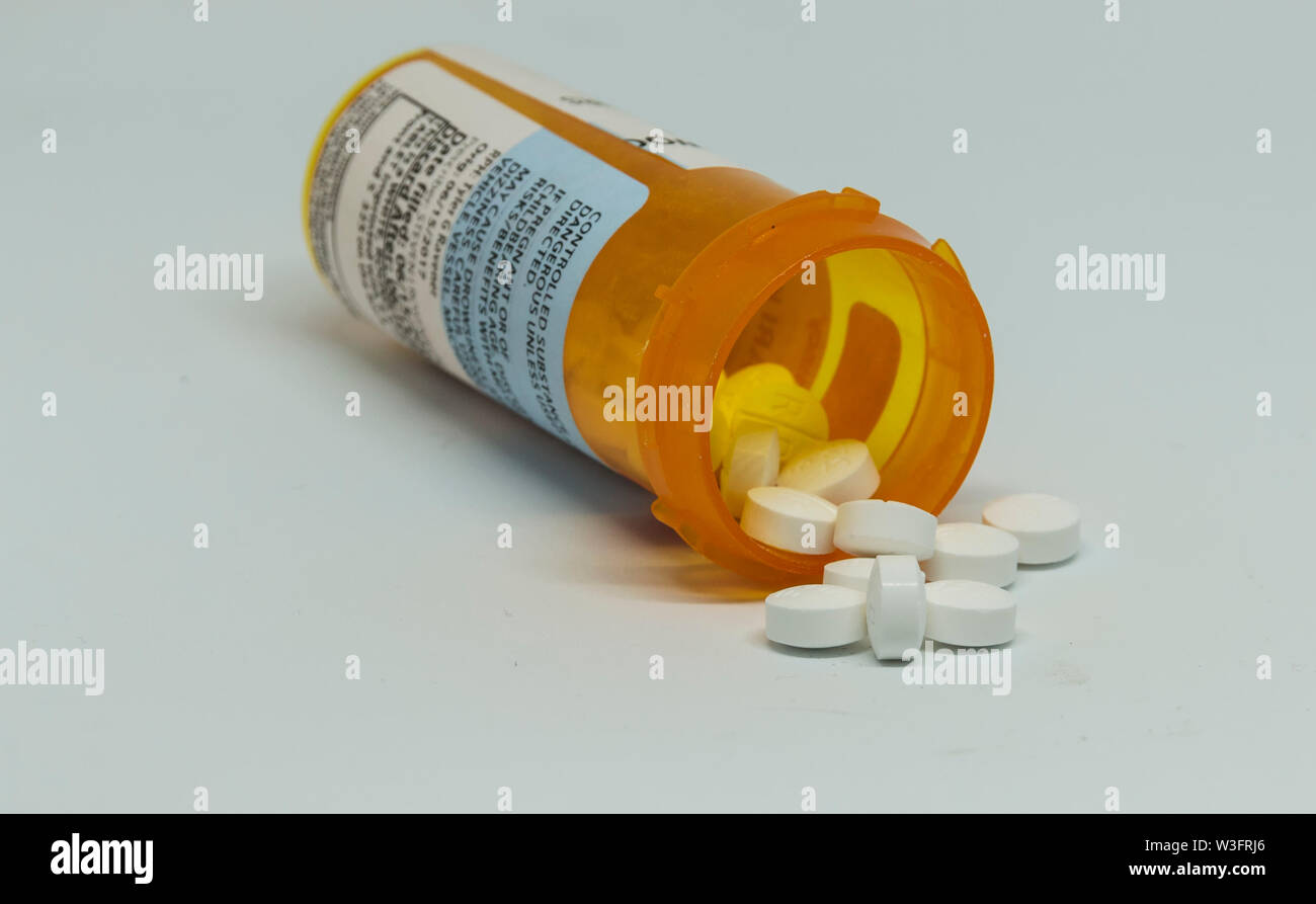 Pille Flasche auf seiner Seite mit kontrollierten Substanz pillen Herausfallen aus der Flasche mit einem weißen Hintergrund. Stockfoto