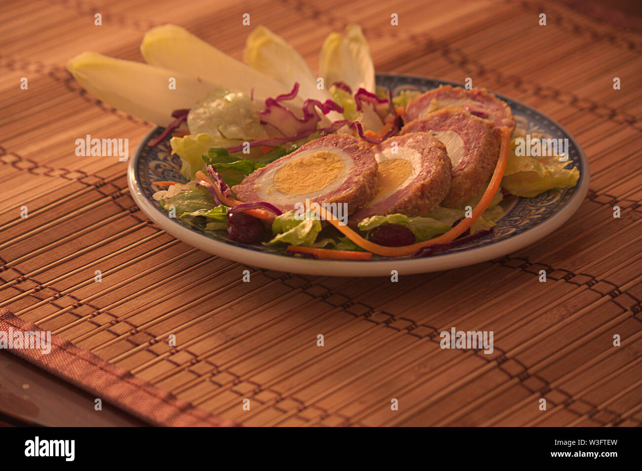 Platte mit einer Portion schottische Eier mit etwas Gemüse mit Kochen. Dunkle Essen Stockfoto