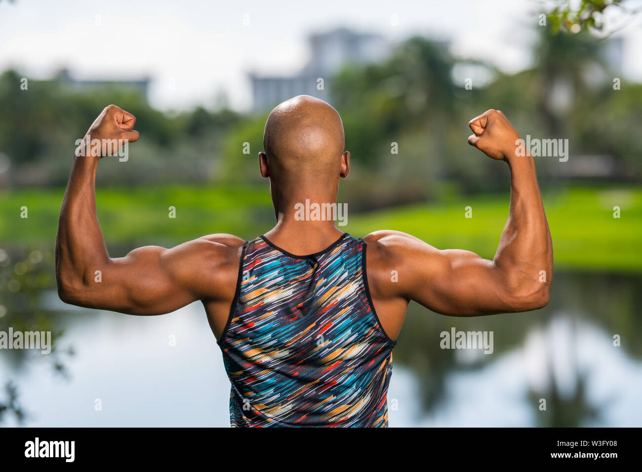 Ansicht der Rückseite Porträt einer starken macho Mann seine Arme biegen. Park See Szene im Hintergrund Stockfoto