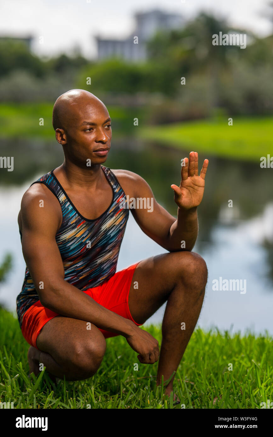 Bild von einem athletischen jungen afrikanischen amerikanischen Mann hocken und winkte aus Kamera. Bild beleuchtet mit Blitzen Stockfoto