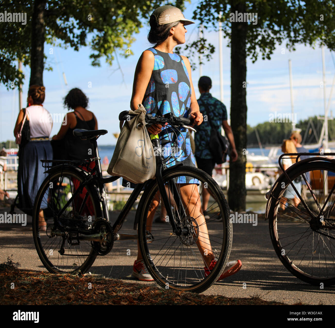 Junge Frau im Sommer Tücher zu Fuß mit dem Fahrrad entlang der Küste Merihaka während Kallio Block Party 2018 in Helsinki, Finnland Stockfoto