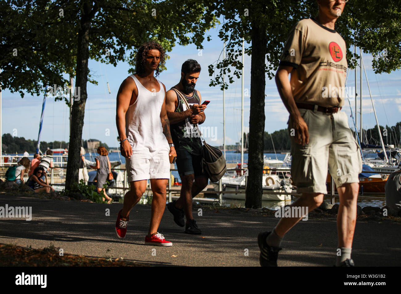 Junge Männer im Sommer Tücher entlang am Meer Merihaka während Kallio Block Party 2018 in Helsinki, Finnland bummeln Stockfoto