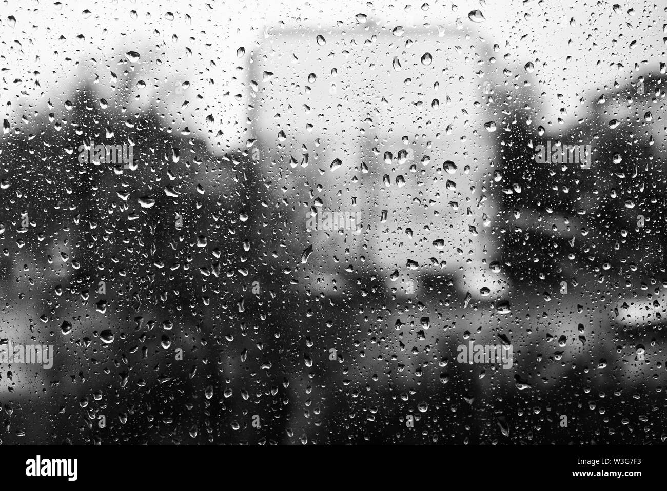 Schwarz-weiß Foto von Tropfen auf dem Glas. Hinter dem gläsernen Gebäude Silhouette Stockfoto