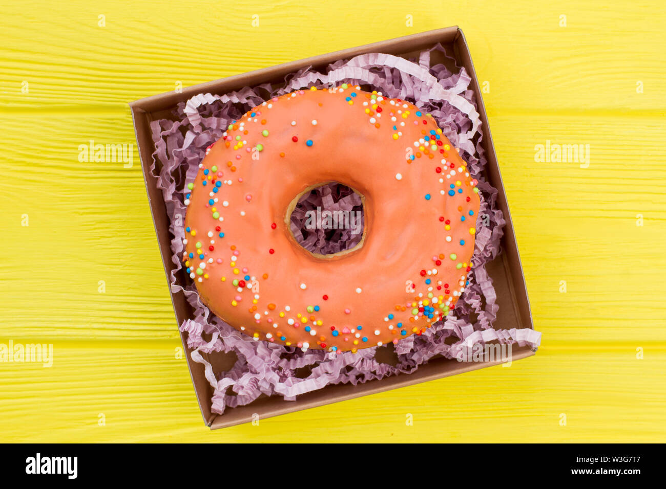 Orange Donut in Geschenkbox. Stockfoto