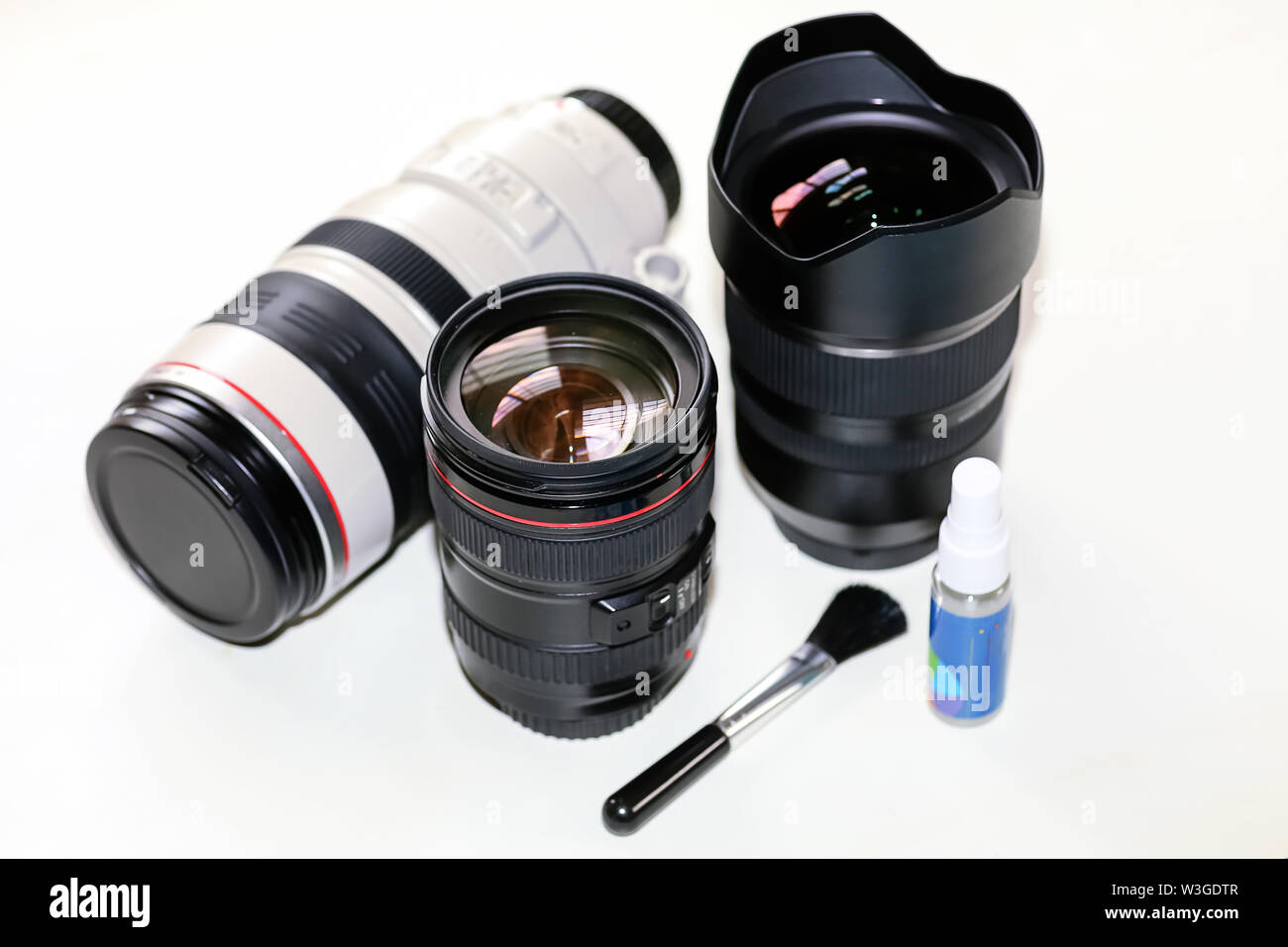 Objektive auf Anzeige von Canon 100-400mm Telezoom objektiv, Tamron 15-30 mm Ultra Wide Angle Lens Cleaning Kit auf weißem Hintergrund Stockfoto