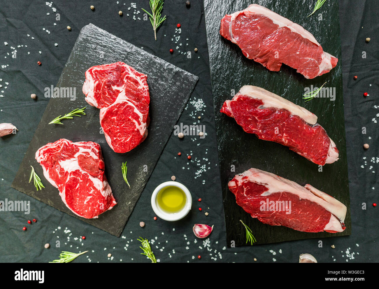 Rindfleisch Rind fleisch Steaks mit Gewürzen und Kräutern auf schwarzem Hintergrund Stockfoto