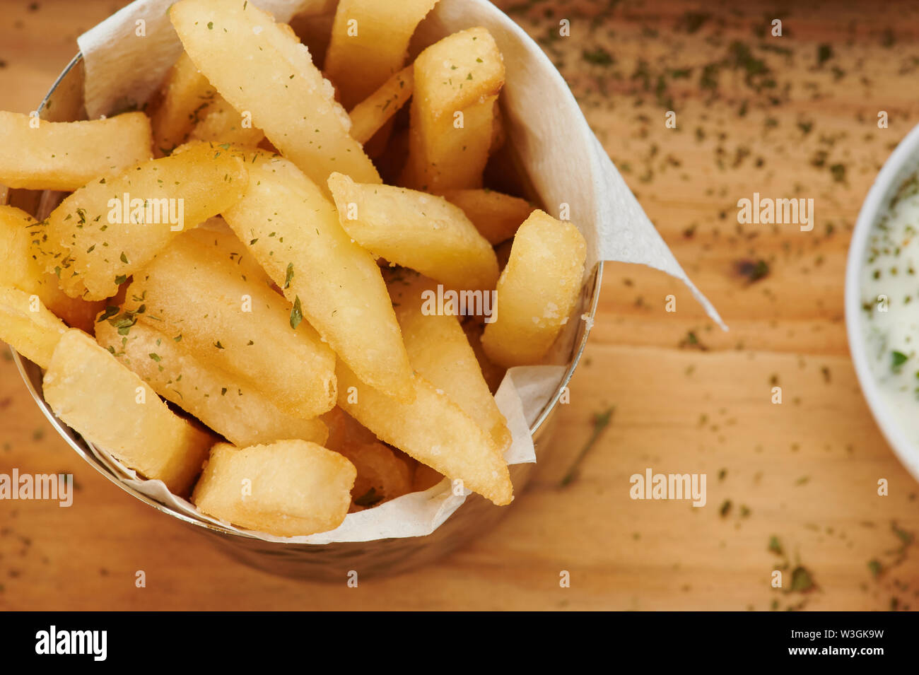 Schüssel mit Pommes Frites und Kräutern auf hölzernen Tisch Stockfoto