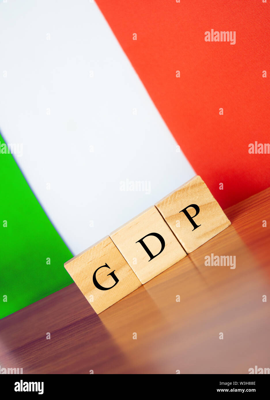 Bruttoinlandsprodukt oder BIP von Italien in Holzblock Buchstaben auf dem Tisch, Italien Flagge als Hintergrund Stockfoto
