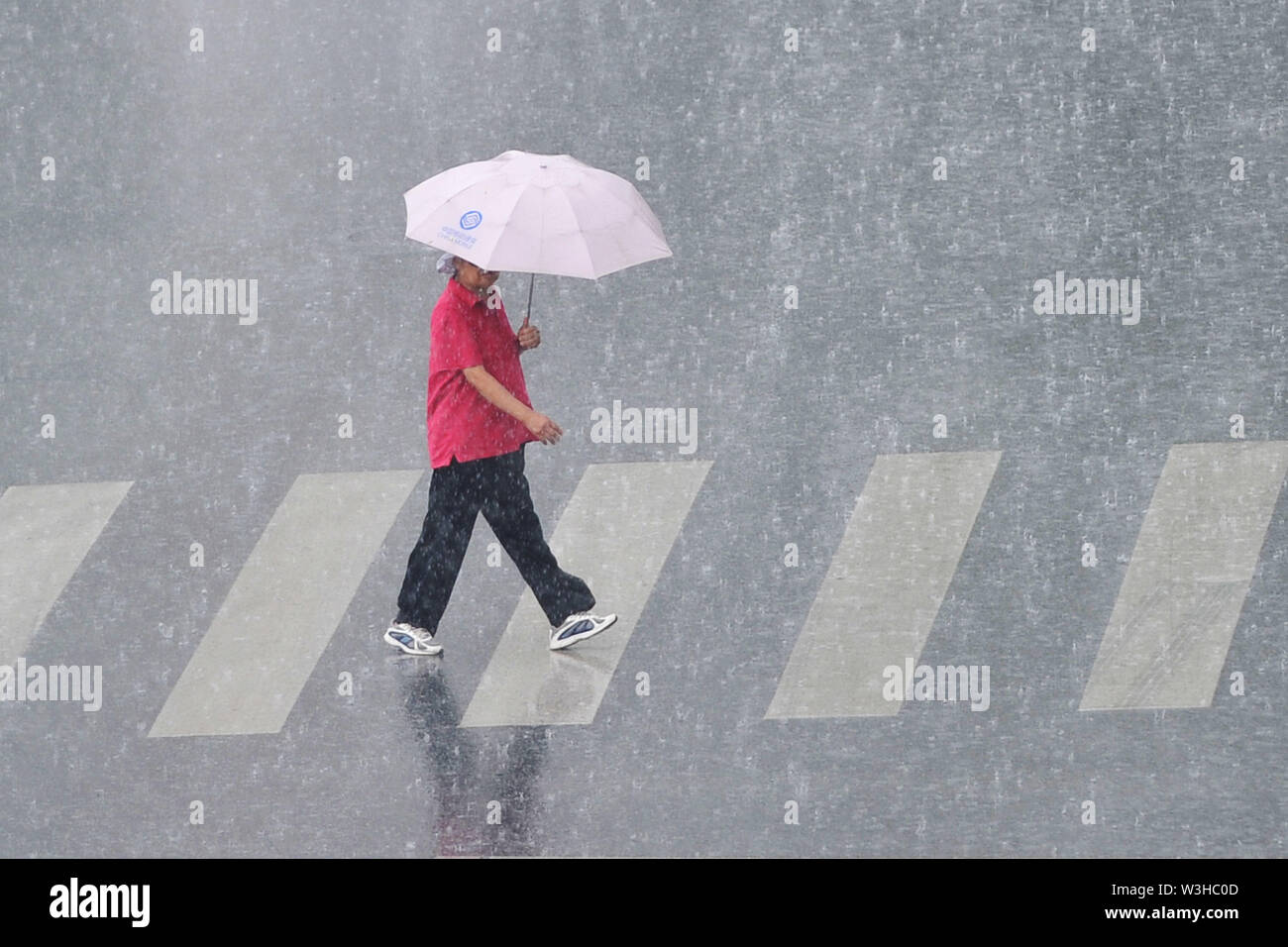 Liaoning, Liaoning, China. 16. Juli, 2019. Liaoning, China - 15. Juli 2019: gehen die Menschen im Regen auf Hua quan Street in Dalian City. Die Liaoning Provincial meteorologische Katastrophe Überwachung und Warnung Center ausgestellt eine blaue Warnsignal für Gewitter Stürme am 13:17 am 15. Juli. Credit: SIPA Asien/ZUMA Draht/Alamy leben Nachrichten Stockfoto
