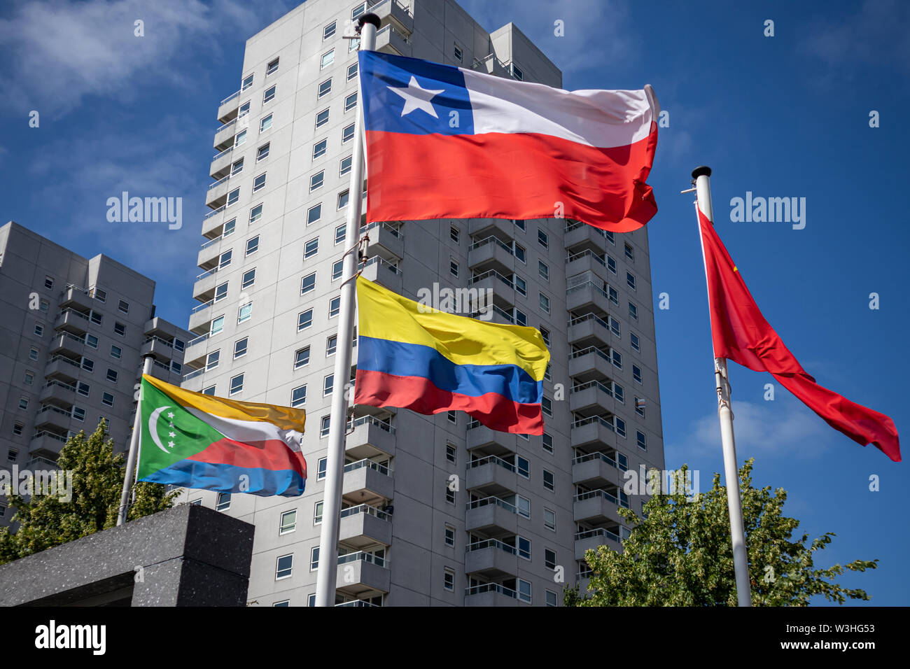Komoren Kolumbien Chile Fahnen. Nationale Symbole winken auf Pole, Hochhaus und dem klaren, blauen Himmel Hintergrund, sonnigen Tag. Rotterdam flag Parade, Stockfoto