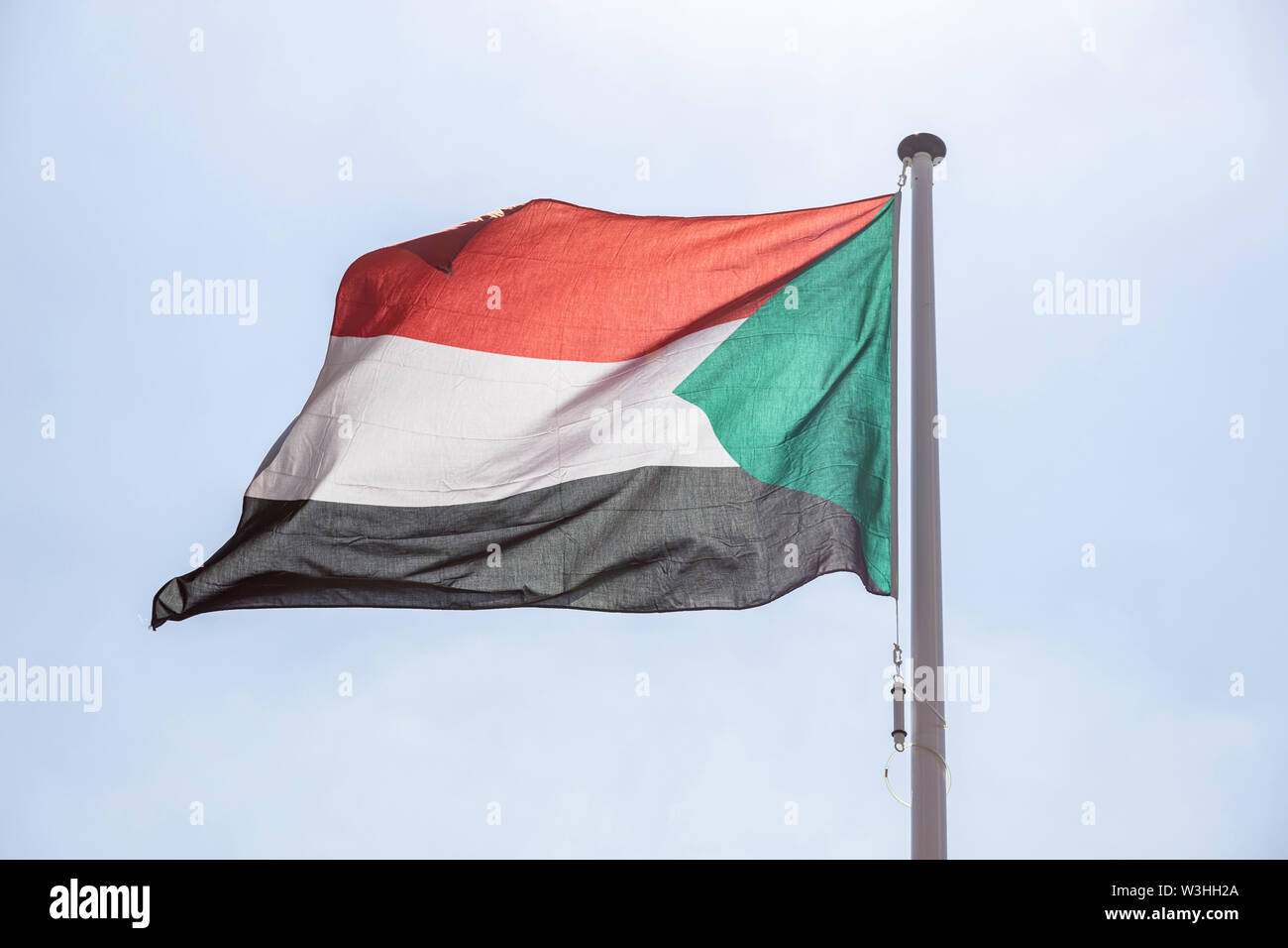 Sudan Fahne, nationales Symbol winken gegen den klaren blauen Himmel, sonnigen Tag Stockfoto