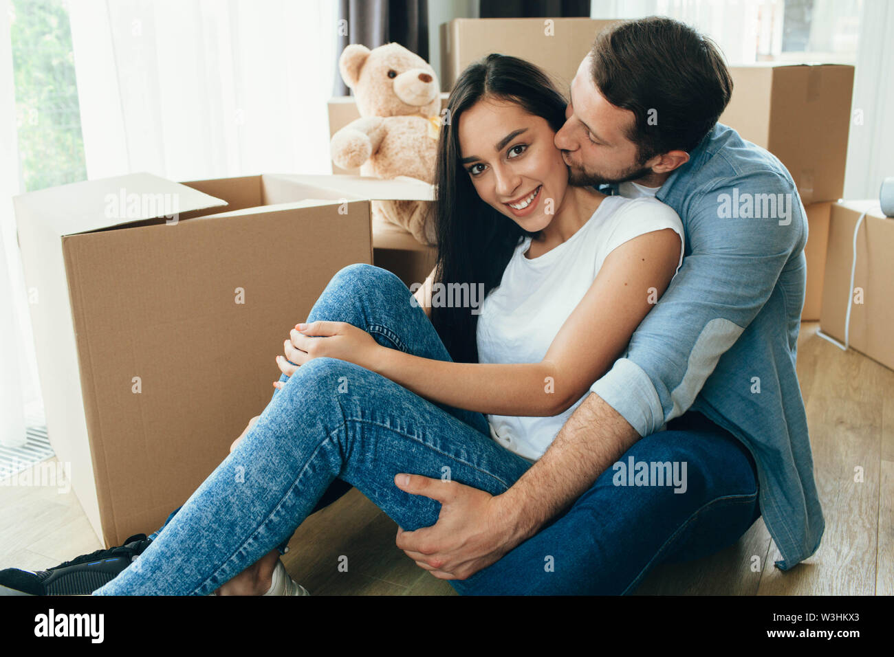 Junges Paar sitzt in der Nähe von Kartons, Umzug neues Haus Stockfoto