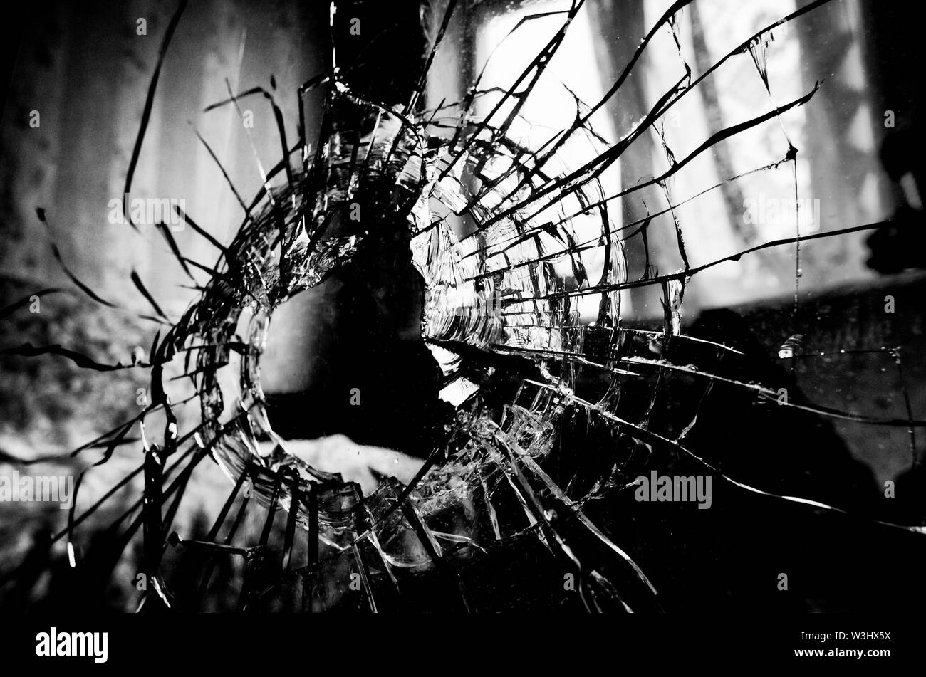 Viele Risse und ein Loch in die Fensterscheibe stilisierten Schwarzweiß-Film und Lomography Stockfoto