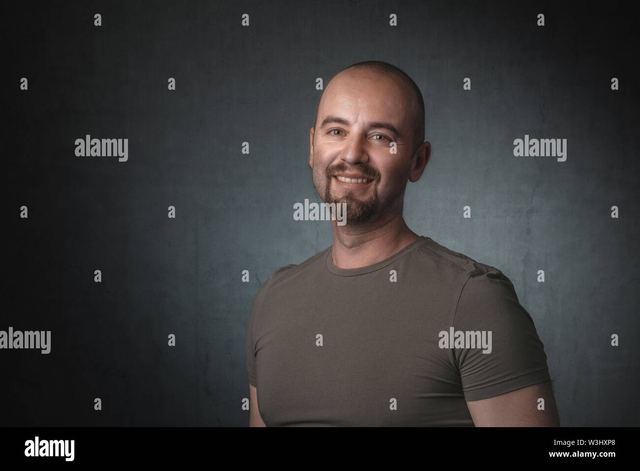 Portrait von lächelnden kaukasischen Mann mit t-shirt und dunklen Hintergrund. Aufnahme im Studio aufgenommen. Stockfoto