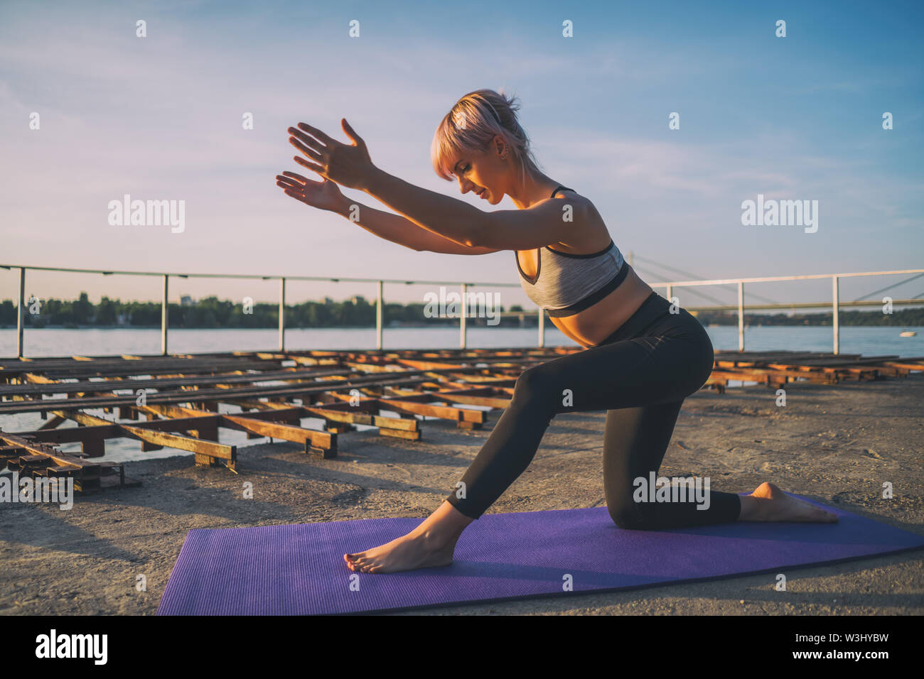 Frau Training Pilates an einem sonnigen Tag. Kniend oberschenkelmuskeldehnung Übung. Stockfoto