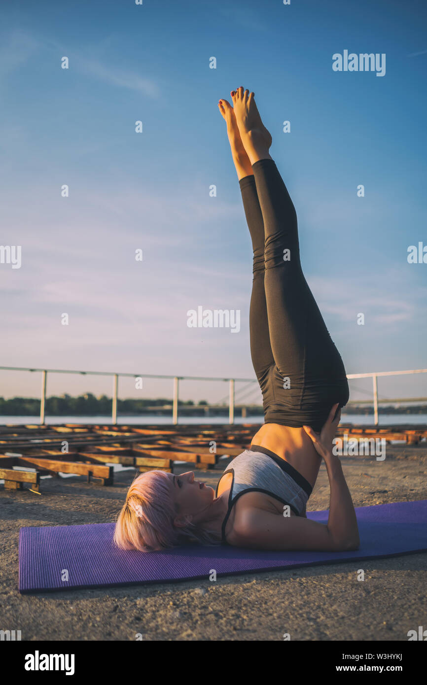 Frau Yoga üben an einem sonnigen Tag. Salamba Sarvangasana/Unterstützt Schulter Stockfoto