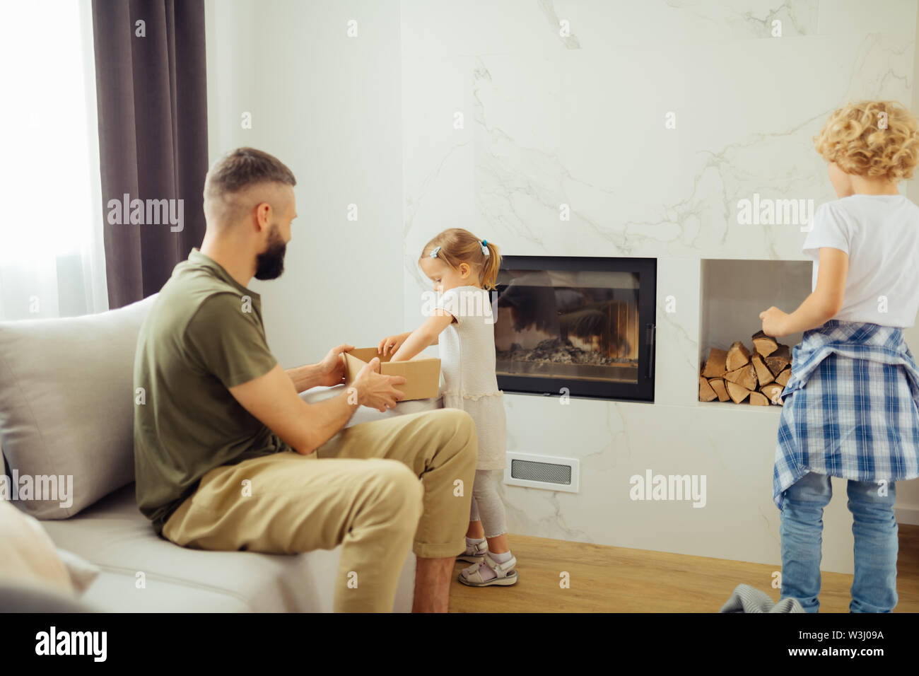 Helfen wollen. Hübsche junge Mädchen in der Nähe von ihrem Vater beim Nehmen von von Sachen aus der Box Stockfoto