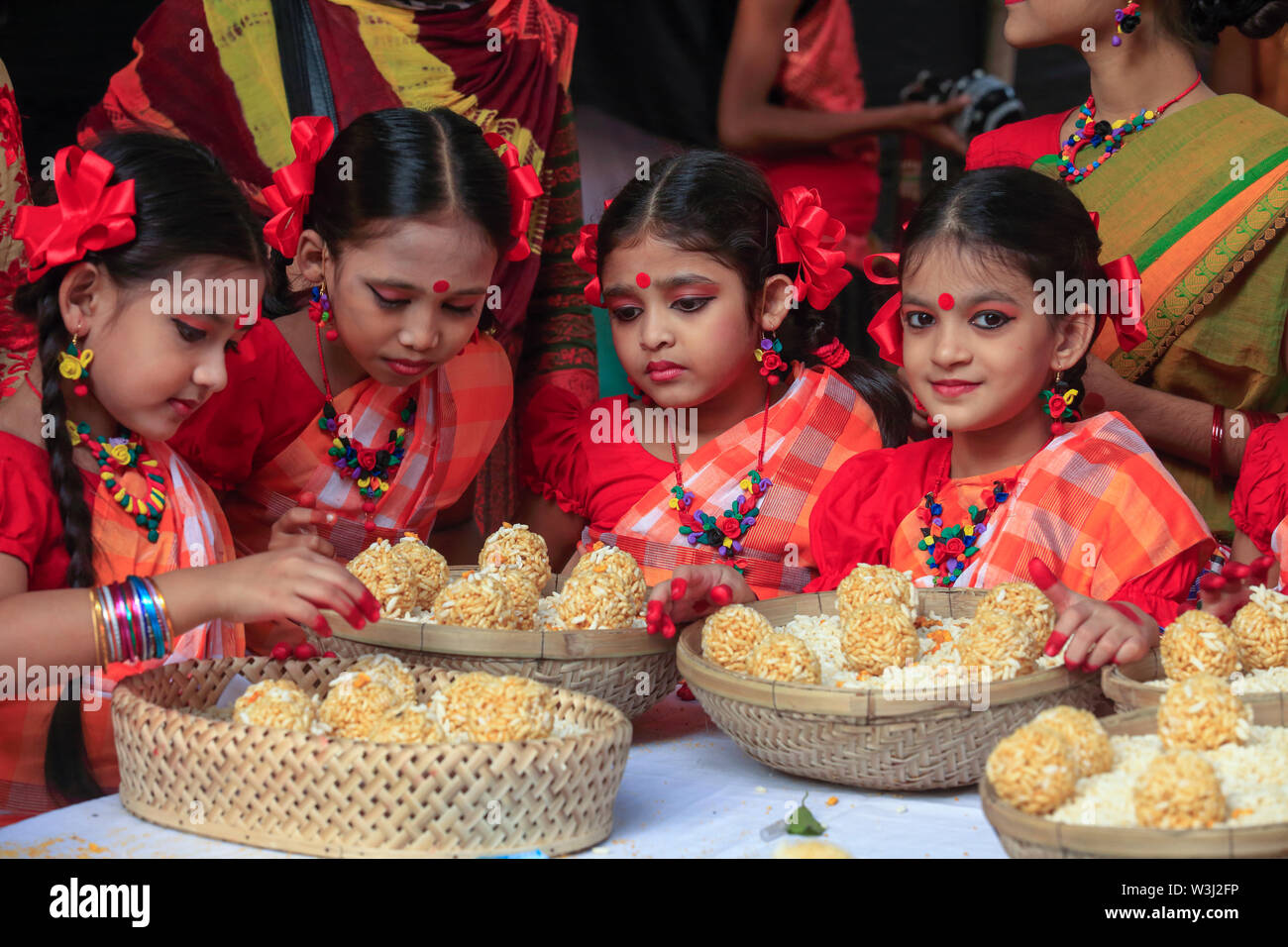Junge Tänzer bieten die Körbe mit traditionellen süßen 'moa' aus puffreis bei 'Nabanna Utsab', die bengalischen Harvest Festival. Dhaka, Bangladesch Stockfoto