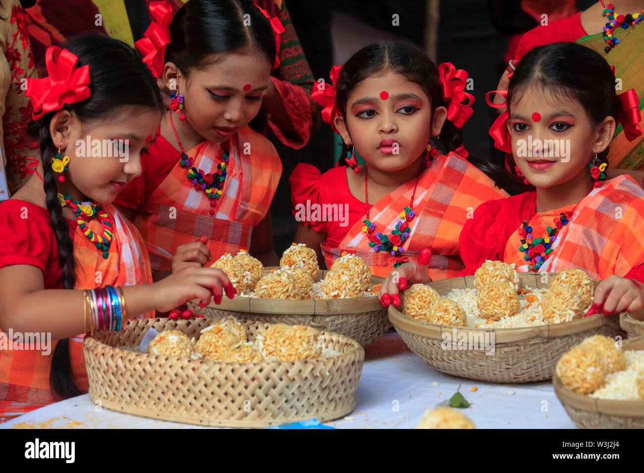 Junge Tänzer bieten die Körbe mit traditionellen süßen 'moa' aus puffreis bei 'Nabanna Utsab', die bengalischen Harvest Festival. Dhaka, Bangladesch Stockfoto
