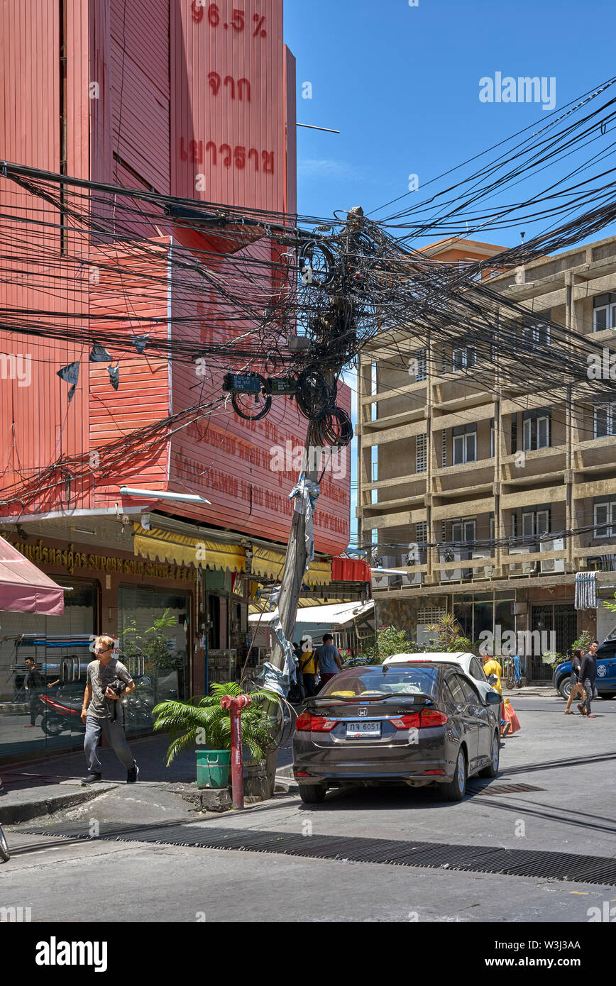 Strommast, der sich in einem prekären Winkel mit dem Auto unter dem Fahrzeug stützt. Thailand, Südostasien Stockfoto