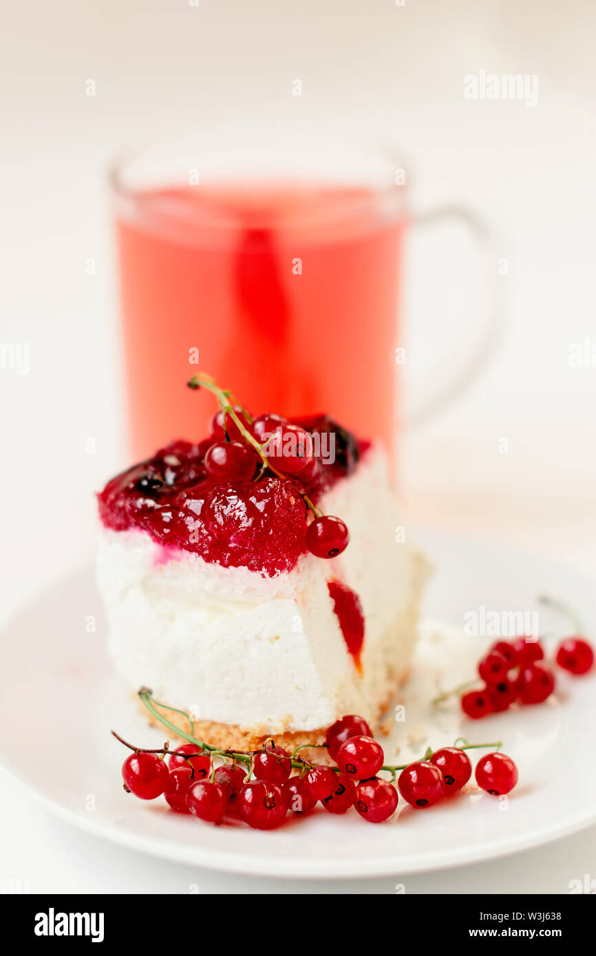 Stück von Souffle Kuchen mit Zweige rote Johannisbeere auf dem Hintergrund der hinter Saft in einer Schale Stockfoto